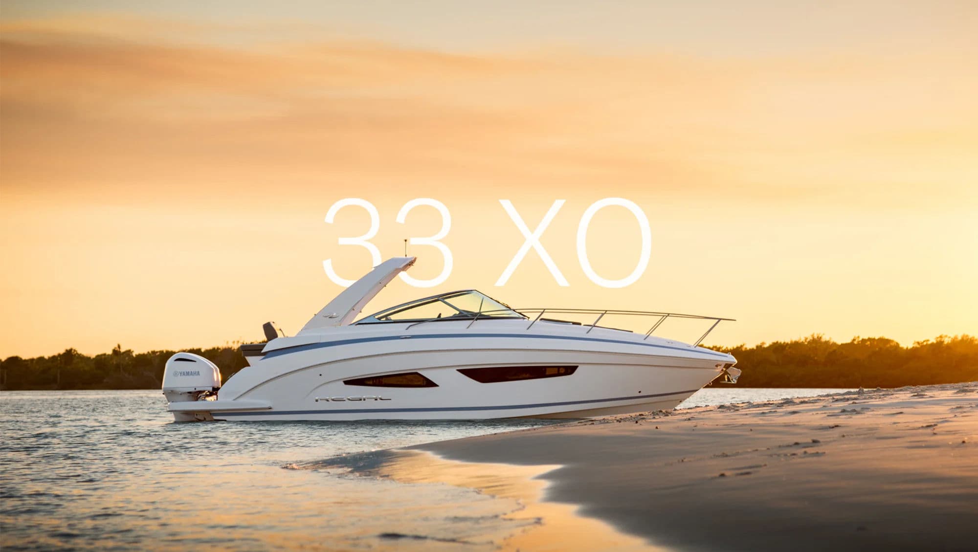 Regal 33 XO przy brzegu w szerokim kadrze hero o zachodzie słońca.